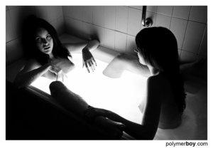 Two hot brunettes browse the web in the bathtub.