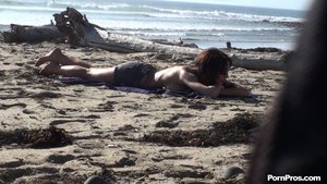 Lying face down on the rocks, she tans topless, by the crashing waves