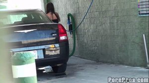 Wearing a very tight, little, black dress, this brunette washes a car