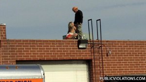 Squatting on a roof top, she pulls his cock out to service it with her moist lips
