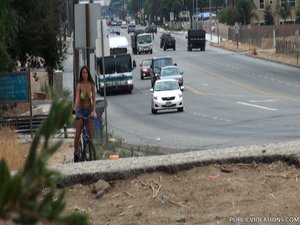 Riding a bike in a bikini top and jean shorts, this brunette whore rides around town
