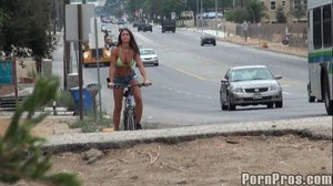 Wearing a lime green bikini top, she rides around the city on a bike