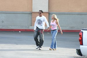 A blonde and her man strut down the street, holding hands