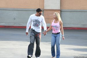 A blonde and her man strut down the street, holding hands